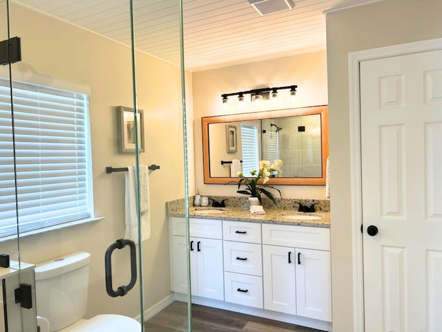 1701 SE Floresta Dr, Port Saint Lucie, FL 34983 - full bath with double vanity, a shower stall, wood finished floors, toilet, and baseboards