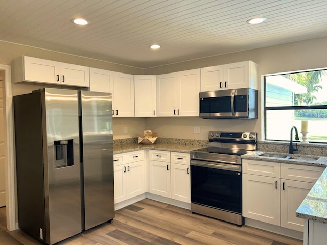 1701 SE Floresta Dr, Port Saint Lucie, FL 34983 - kitchen with stainless steel appliances, a sink, recessed lighting, white cabinetry, and light stone counters