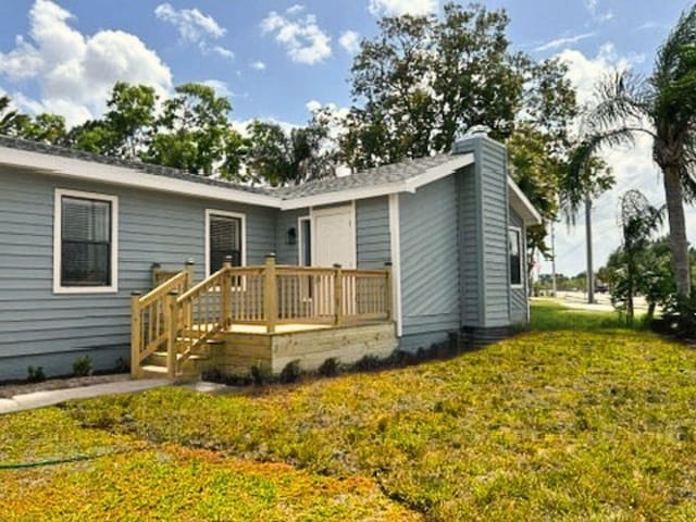 1701 SE Floresta Dr, Port Saint Lucie, FL 34983 - rear view of house with a yard, a chimney, and a wooden deck