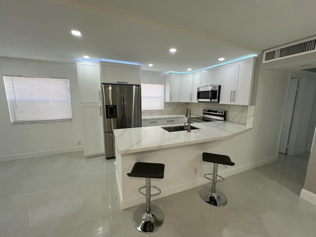kitchen featuring white cabinetry, a sink, visible vents, a peninsula, and appliances with stainless steel finishes