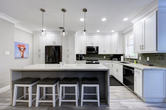 kitchen with black appliances, a sink, tasteful backsplash, a kitchen island, and white cabinetry