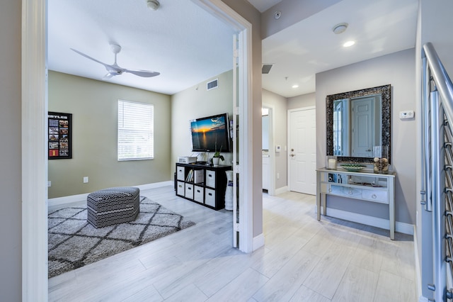 foyer featuring a ceiling fan, baseboards, and light wood finished floors