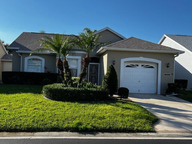 1047 NW Tuscany Dr, Port Saint Lucie, FL 34986 - ranch-style house with driveway, an attached garage, a front yard, stucco siding, and a shingled roof