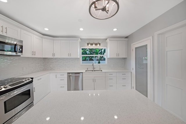 kitchen featuring appliances with stainless steel finishes, a sink, white cabinetry, light stone counters, and recessed lighting