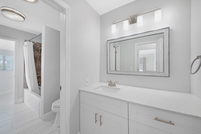 bathroom featuring toilet, vanity, shower / tub combo with curtain, and baseboards