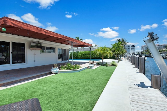 view of green lawn with an outdoor pool and a boat dock