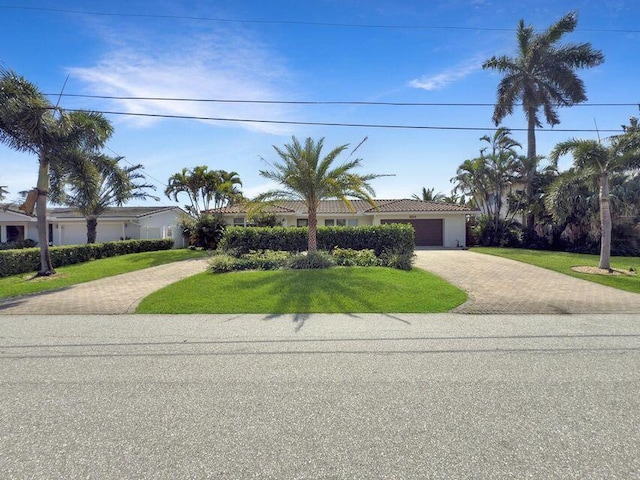 ranch-style house with decorative driveway, a front yard, an attached garage, stucco siding, and a tiled roof