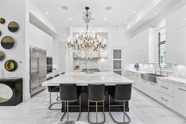 8388 Del Prado Dr, Delray Beach, FL 33446 - kitchen with built in appliances, modern cabinets, white cabinets, backsplash, and a large island