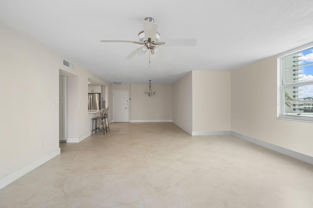 unfurnished living room with ceiling fan with notable chandelier, visible vents, and baseboards