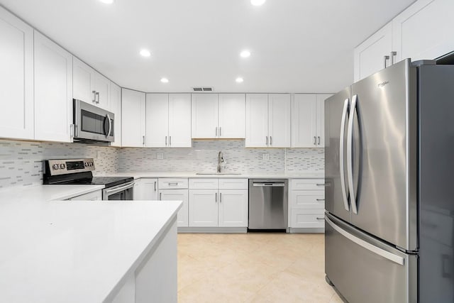 kitchen with decorative backsplash, light countertops, a sink, and appliances with stainless steel finishes