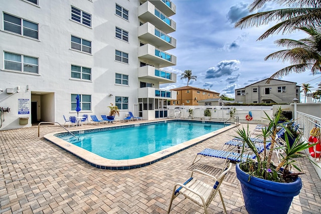 community pool with fence and a patio area