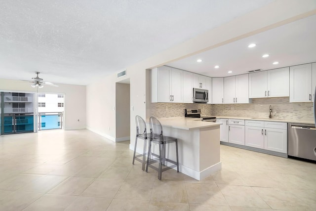 kitchen featuring light countertops, visible vents, stainless steel appliances, a sink, and backsplash
