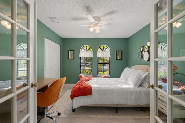 bedroom featuring french doors, a textured ceiling, visible vents, a ceiling fan, and a closet