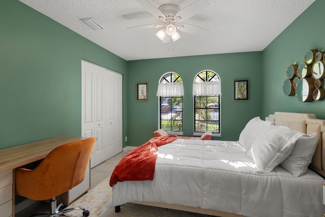 bedroom featuring a closet, a textured ceiling, visible vents, and a ceiling fan