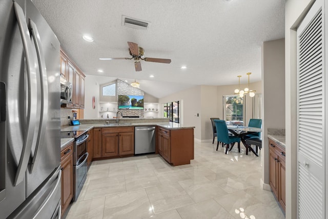 kitchen featuring vaulted ceiling, a sink, appliances with stainless steel finishes, a peninsula, and brown cabinets