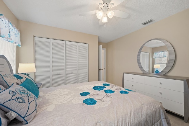 bedroom with visible vents, a closet, ceiling fan, and a textured ceiling