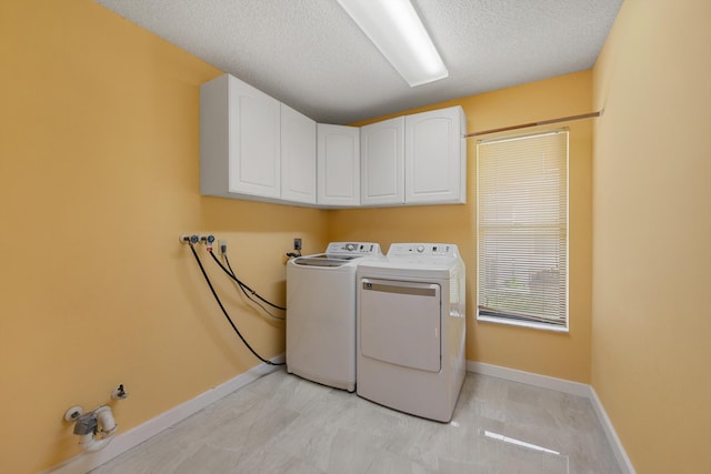 laundry room with baseboards, cabinet space, a textured ceiling, and washing machine and clothes dryer