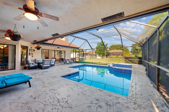 view of pool featuring glass enclosure, ceiling fan, a pool with connected hot tub, and a patio