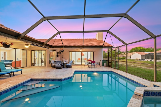 pool at dusk featuring glass enclosure and a patio area