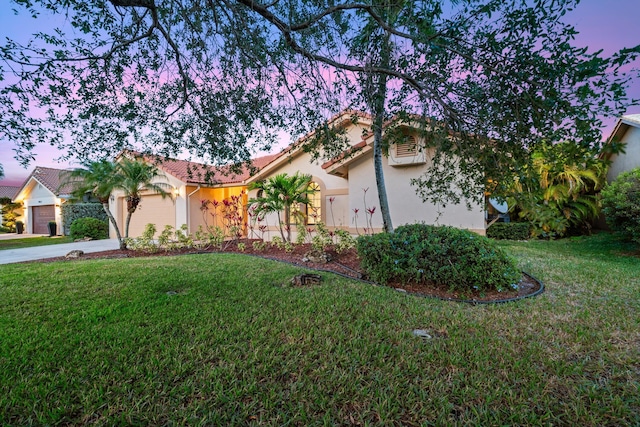 view of front of home with an attached garage, a tile roof, concrete driveway, and a yard