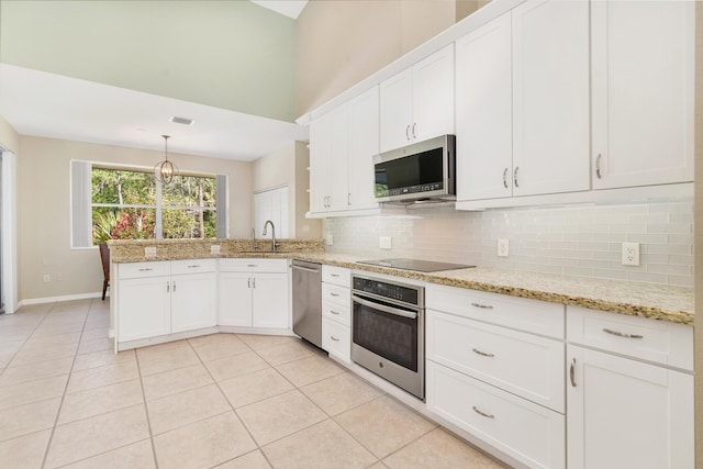 kitchen featuring white cabinetry, tasteful backsplash, a peninsula, light tile patterned floors, and stainless steel appliances