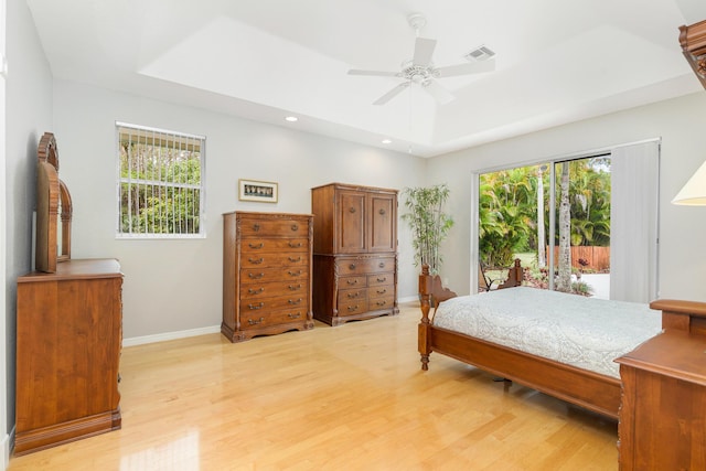 bedroom with light wood-style flooring, visible vents, multiple windows, and a raised ceiling