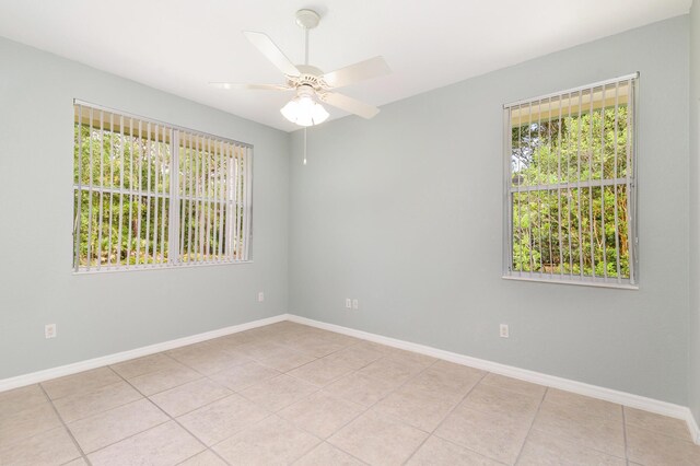 spare room featuring a ceiling fan, light tile patterned floors, and baseboards