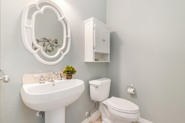 bathroom featuring toilet, a sink, and baseboards