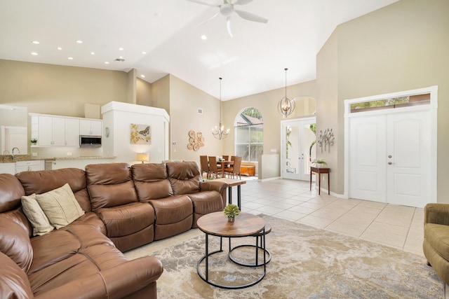living area with high vaulted ceiling, baseboards, light tile patterned floors, ceiling fan with notable chandelier, and recessed lighting