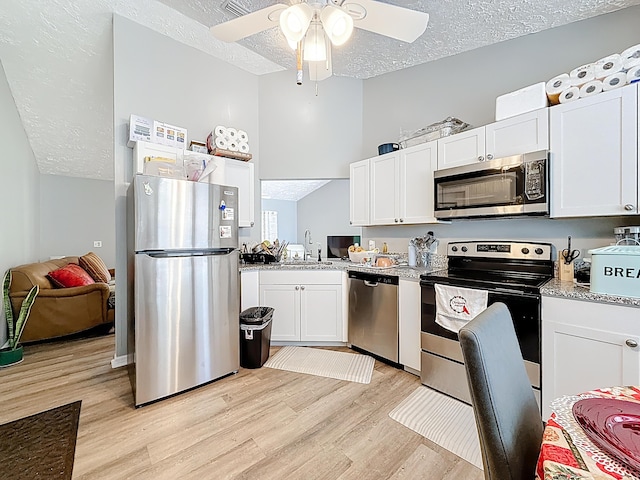 kitchen featuring white cabinetry, stainless steel appliances, a textured ceiling, light wood finished floors, and a ceiling fan