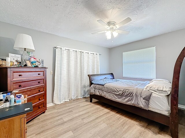 bedroom with a ceiling fan, light wood finished floors, and a textured ceiling