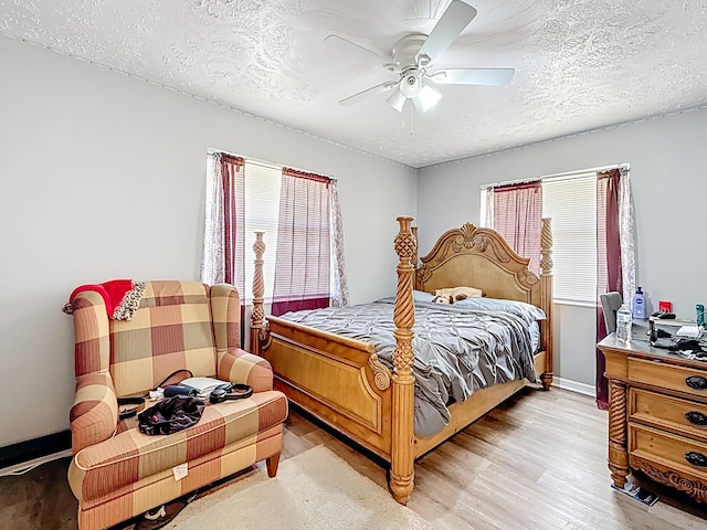 bedroom with a ceiling fan, light wood-style flooring, baseboards, and a textured ceiling