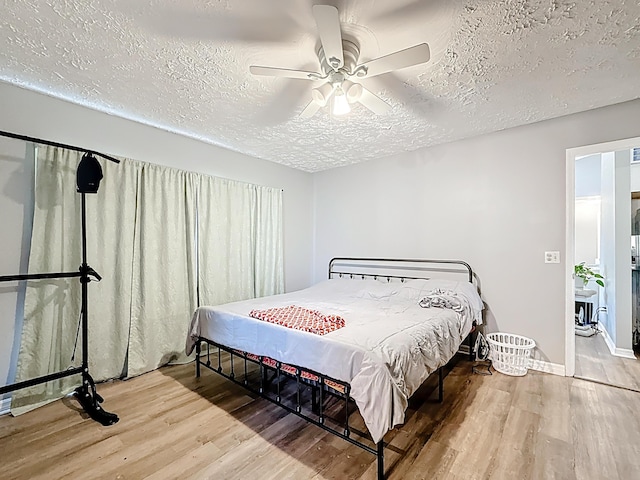 bedroom with baseboards, a textured ceiling, wood finished floors, and ceiling fan