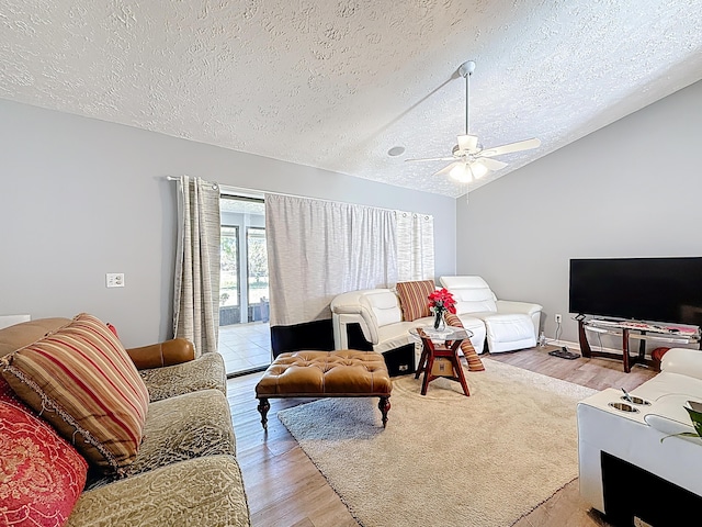 living room with a textured ceiling, lofted ceiling, ceiling fan, and light wood-style floors