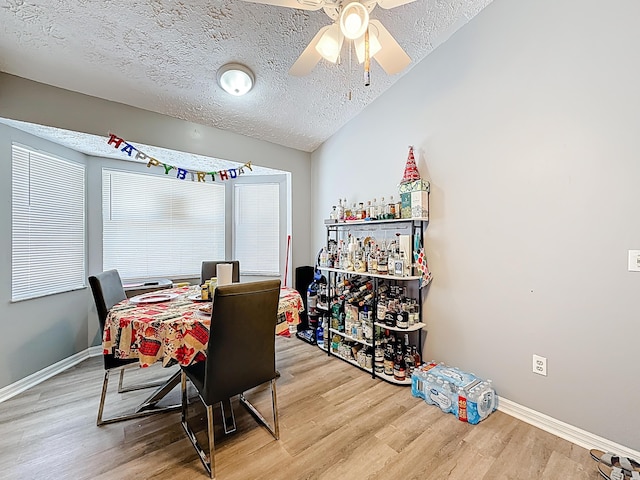 dining space featuring vaulted ceiling, a textured ceiling, light wood-type flooring, baseboards, and ceiling fan