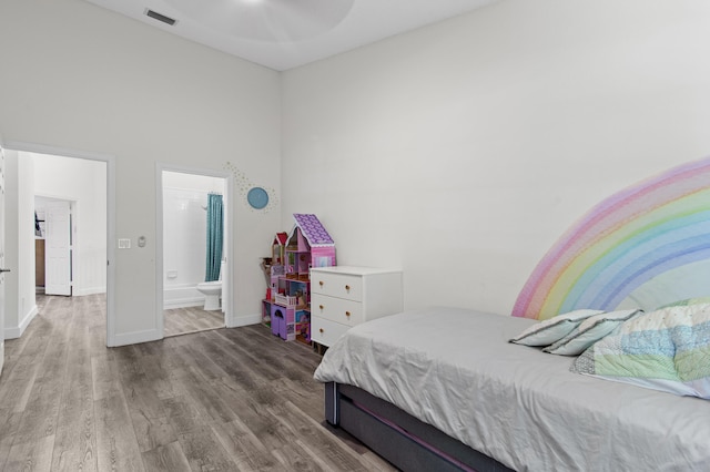 9448 Boca River Cir, Boca Raton, FL 33434 - bedroom with ensuite bathroom, visible vents, baseboards, a towering ceiling, and wood finished floors