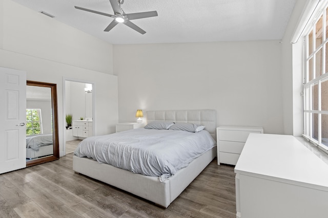 9448 Boca River Cir, Boca Raton, FL 33434 - bedroom with connected bathroom, wood finished floors, a textured ceiling, lofted ceiling, and visible vents