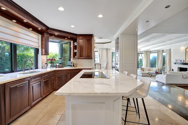 kitchen featuring a breakfast bar, black electric stovetop, open floor plan, a kitchen island, and a sink