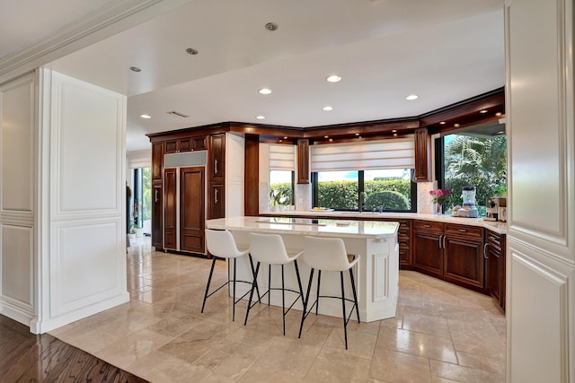 kitchen with paneled fridge, light stone countertops, recessed lighting, a center island, and a breakfast bar area