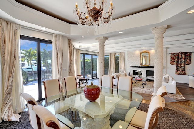 dining area featuring ornamental molding, a notable chandelier, decorative columns, and a raised ceiling