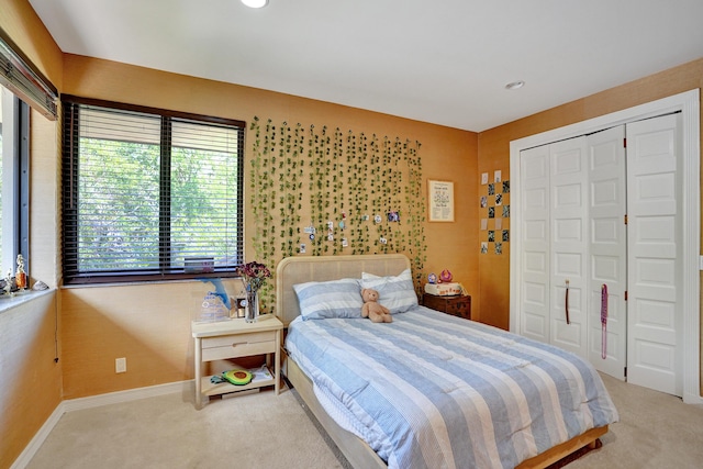 carpeted bedroom featuring a closet and baseboards