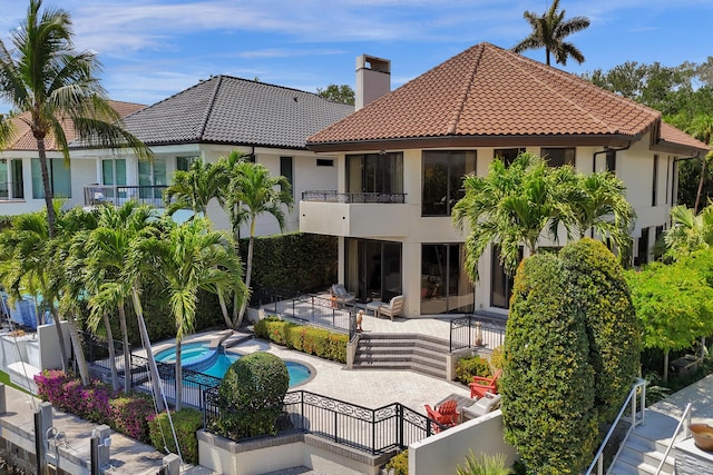 rear view of property with a patio area, a balcony, a fenced backyard, and a tiled roof