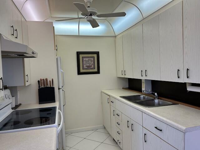 kitchen featuring light countertops, a ceiling fan, under cabinet range hood, a sink, and white range with electric cooktop