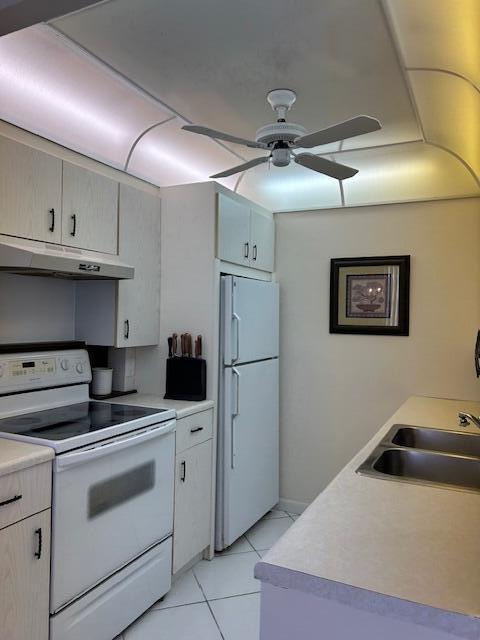 kitchen featuring light countertops, white appliances, under cabinet range hood, a sink, and ceiling fan