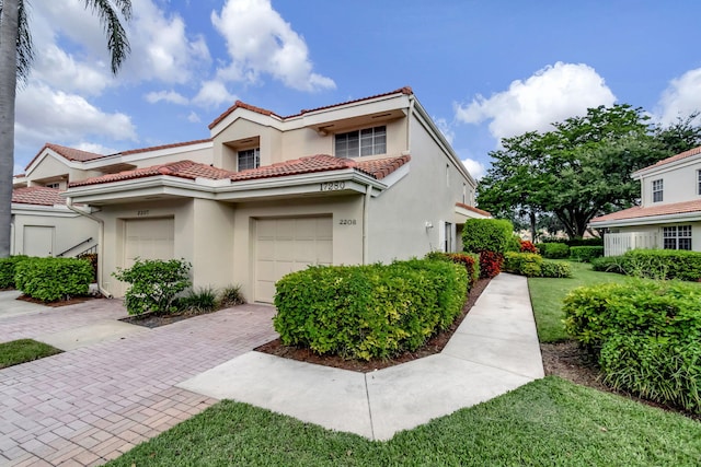 view of front of home featuring stucco siding, a tile roof, an attached garage, and decorative driveway