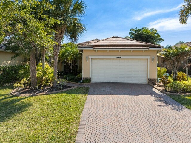 9686 SW Glenbrook Dr, Port Saint Lucie, FL 34987 - ranch-style house featuring a tile roof, stucco siding, an attached garage, decorative driveway, and a front yard