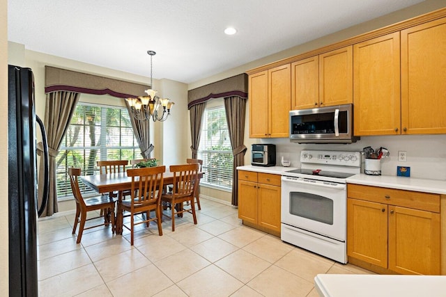 9686 SW Glenbrook Dr, Port Saint Lucie, FL 34987 - kitchen with light countertops, a chandelier, stainless steel microwave, electric range, and freestanding refrigerator