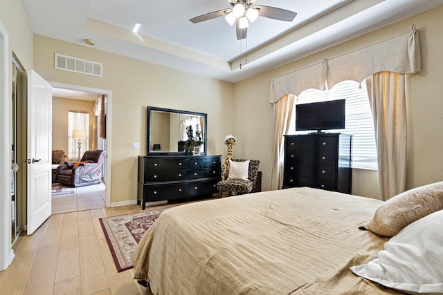 9686 SW Glenbrook Dr, Port Saint Lucie, FL 34987 - bedroom with baseboards, a raised ceiling, hardwood / wood-style flooring, visible vents, and a ceiling fan