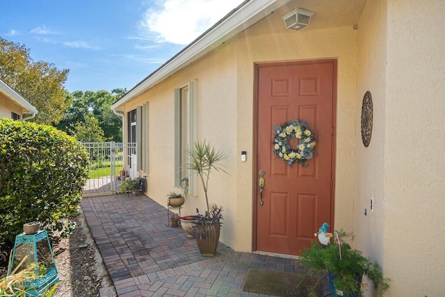 9686 SW Glenbrook Dr, Port Saint Lucie, FL 34987 - view of exterior entry featuring stucco siding, a gate, fence, and a patio area