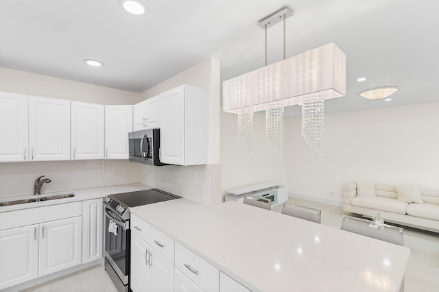 361 Normandy H, Delray Beach, FL 33484 - kitchen featuring range with electric stovetop, a sink, stainless steel microwave, white cabinets, and recessed lighting